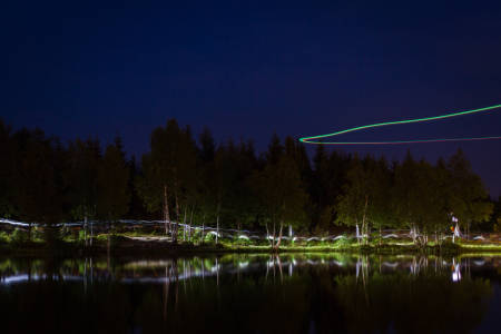Hodelyktene danner kunstneriske striper langs vannkanten. Fra luften filmer en drone løperne.